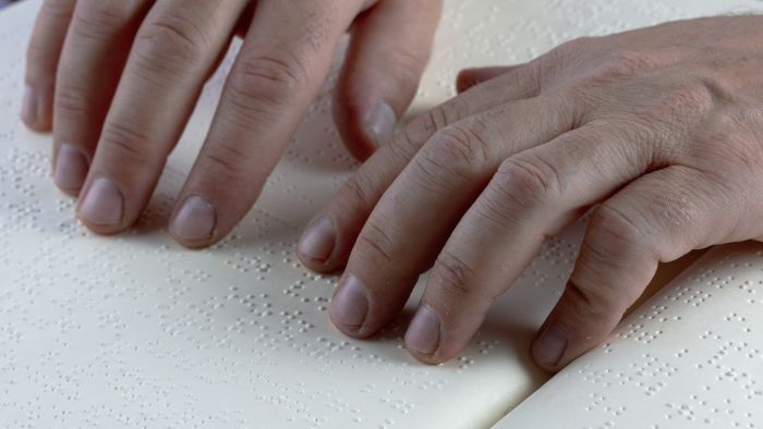 Hände ertasten einen Text in Braille-Schrift. Sechs Punkte, die die Welt veränderten