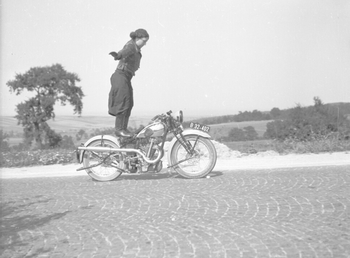 Rennfahrerinnenporträt: Anny Deim, stehend auf einem Motorrad, 1935