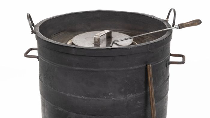 Schwarze Kesselfeuerstelle auf Rollen (Maroniofen) mit Schaufel und Eimer für Kohle Der Maroniofen – ein winterliches Stadtmöbel