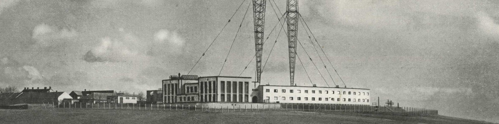 Historisches Schwarzweißfoto der Sendeanlage Bisamberg mit zwei hohen Antennen und einem Gebäudekomplex